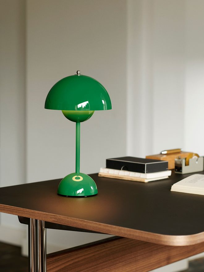 &Tradition's cordless Flowerpot VP9 table lamp in a signal green shade, placed on a work desk.