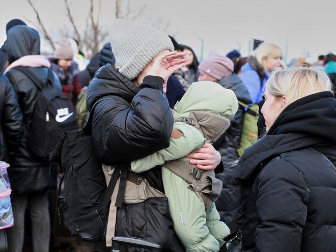A woman wiping her tears and holding a baby in her arms