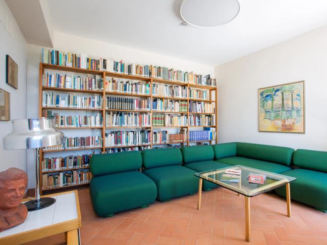 Villa Lante library with a green corner sofa, glass coffee table and a large bookcase