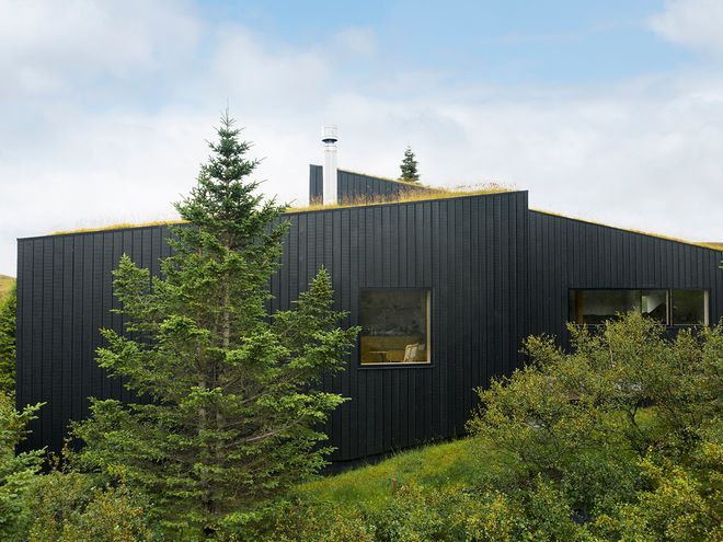 An image of the Holiday home by Þingvallavatn by KRADS architects: a leisure home located in Iceland in the middle of a picturesque scenery. This image features the buildings black facade.