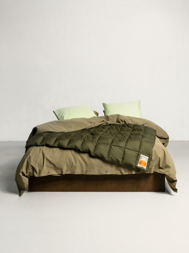A close-up of a bed with different green shaded Reboco bed linen
