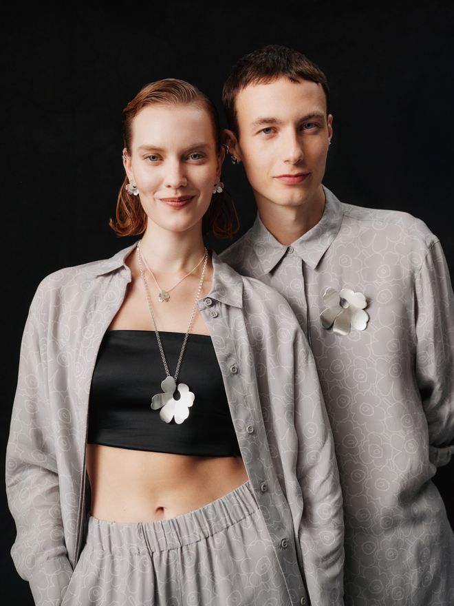 Kalevala x Marimekko silver necklace and brooch worn by two smiling models.