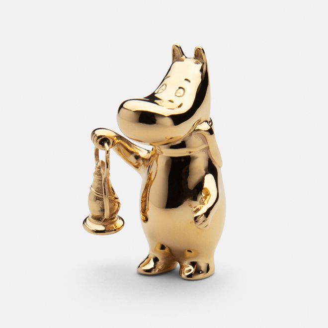 A gilded Moomintroll figurine carries a lantern.