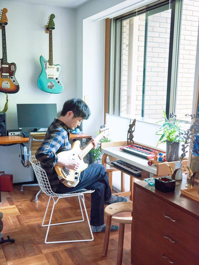 Man sitting in front of a desk and playing guitar