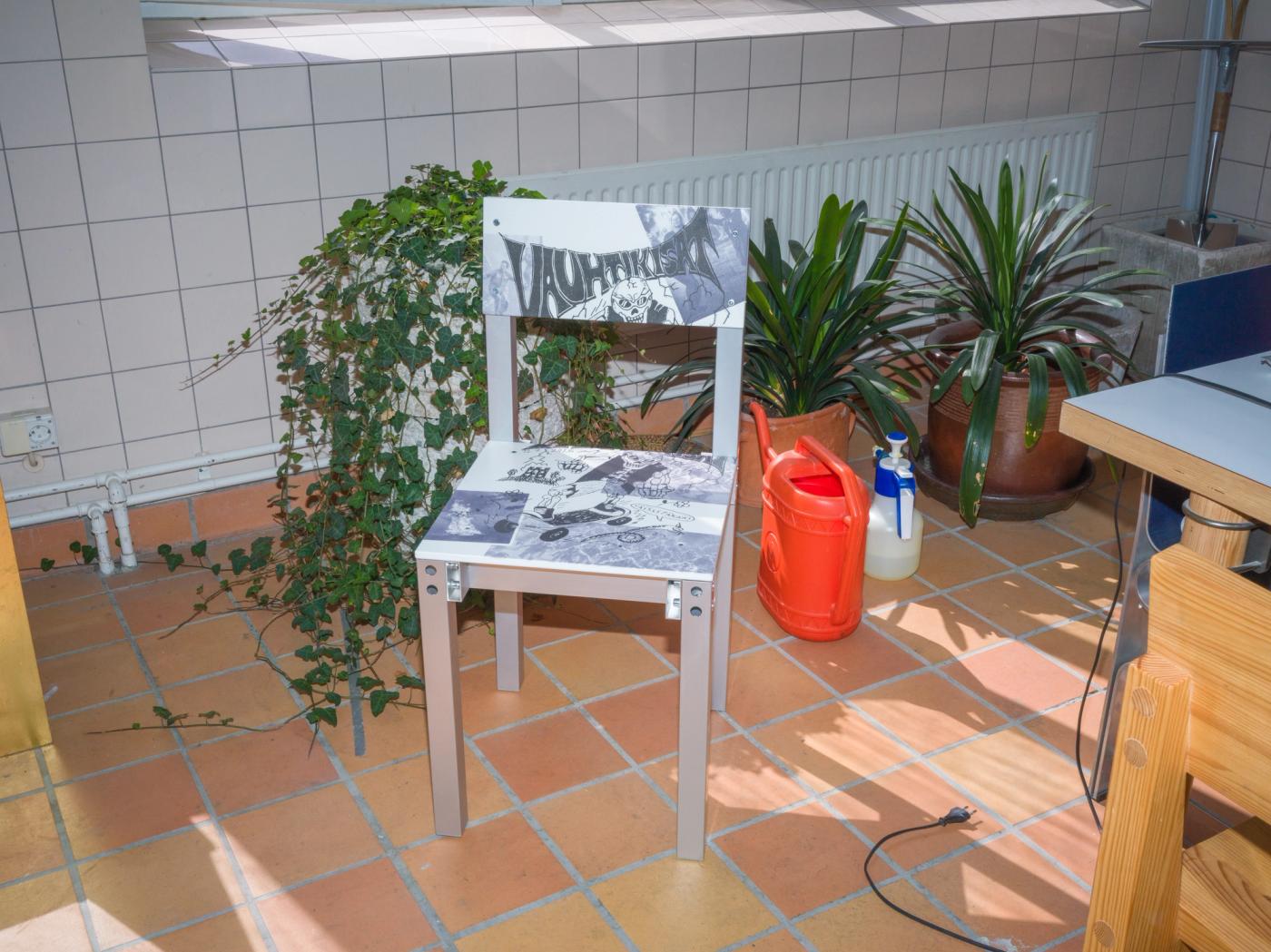 The patterned chair stands among potted plants and a watering can on a tiled floor.