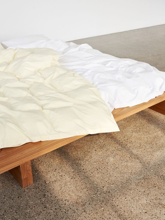 Tekla's faded yellow and white duvet cover styled on a bed.