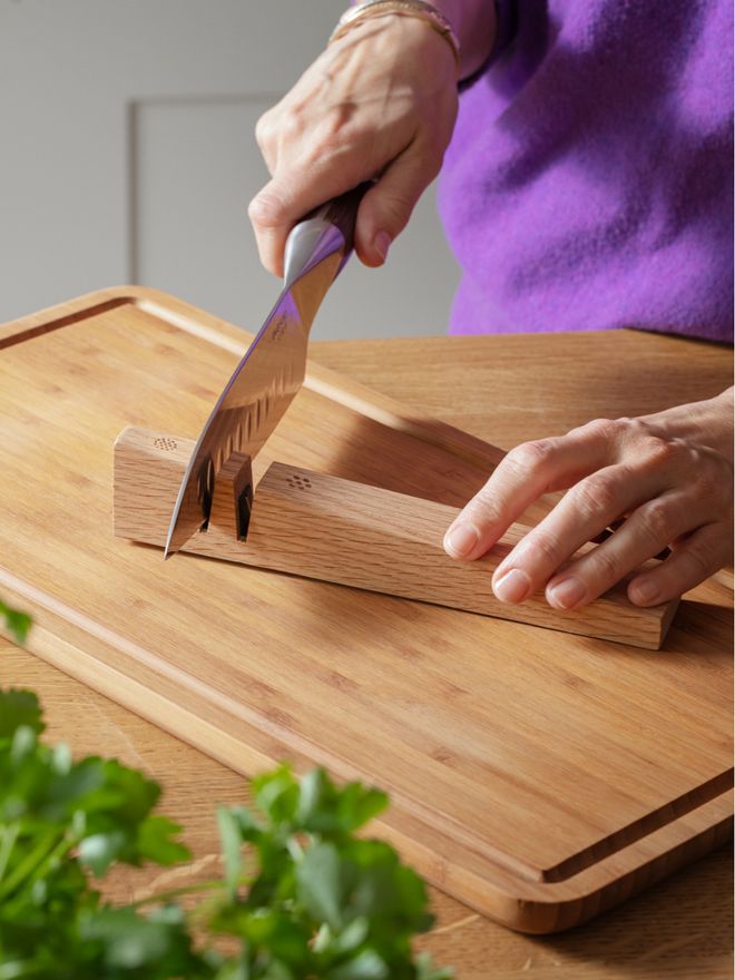 Close-up of a hand sharpening a Japanese-style kitchen knife with Eva Solo’s Eastern knife sharpener on a wooden surface