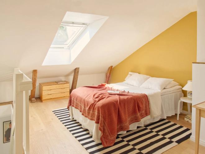A bedroom with a skylight in the upstairs of a wooden house