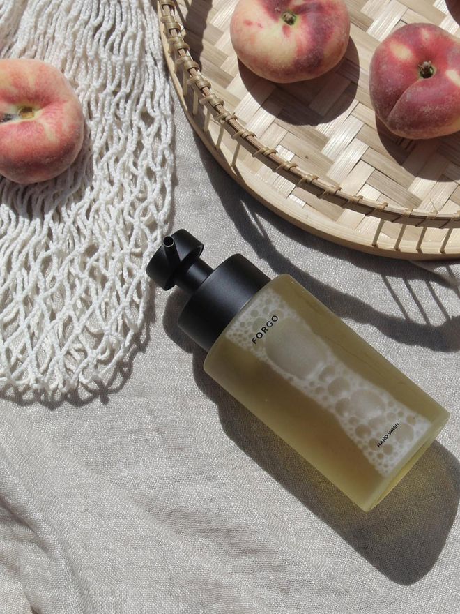 An image of Forgo's hand soap on a table with a few peaches.