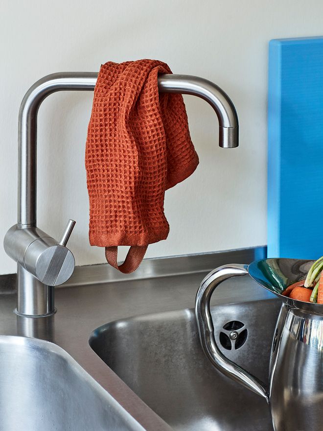 Hay's orange cotton dish cloth hanged over a faucet.