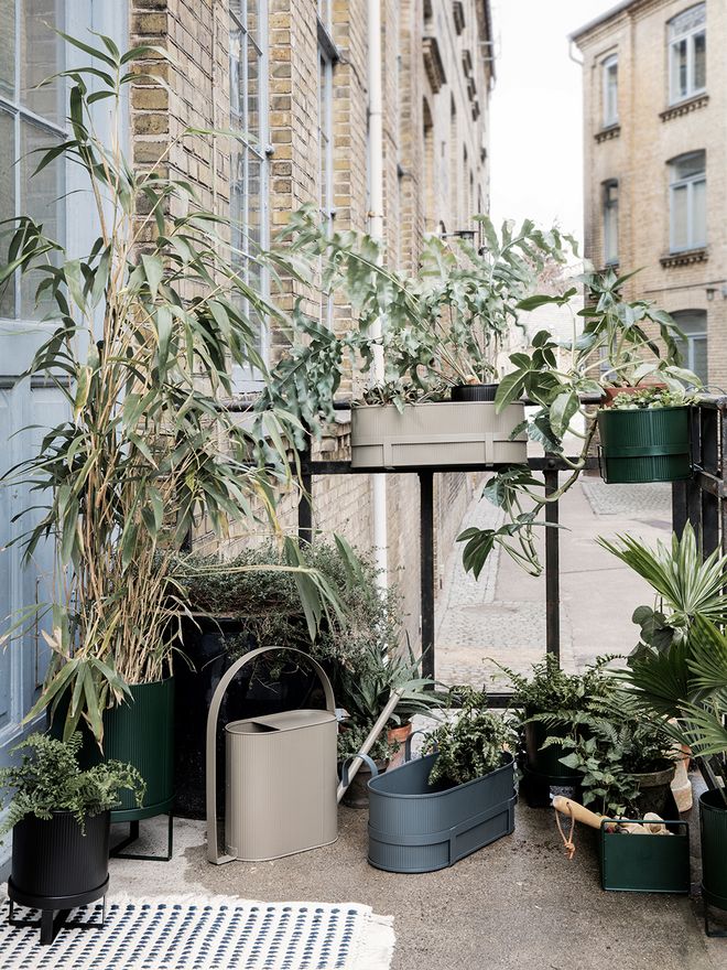 Ferm Living's Bau balcony boxes and pots on a balcony with a city view.