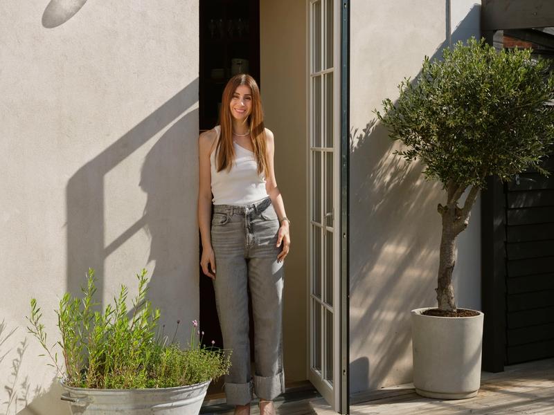 Portrait of Nadia Lassen standing in the doorway of her light-filled Frederiksberg villa, welcoming visitors into her home.