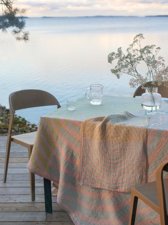 Summer lake view and terrace where table is set with glassware and vase full of flowers