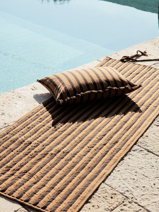 Ferm Living's Way cushion beside a swimming pool.