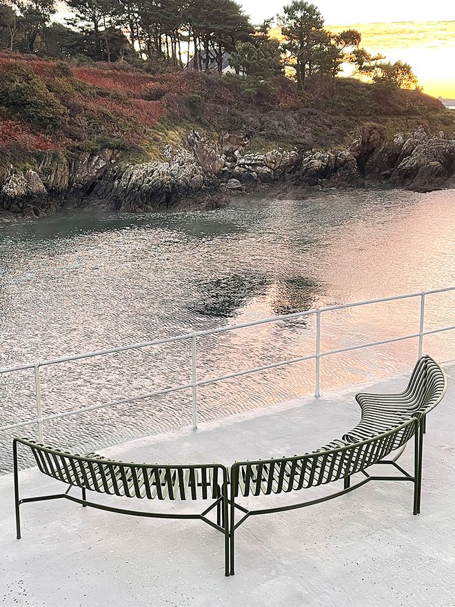 HAY’s Palissade series benches set in a curved shape on the dock, overlooking the waterfront at sunset.