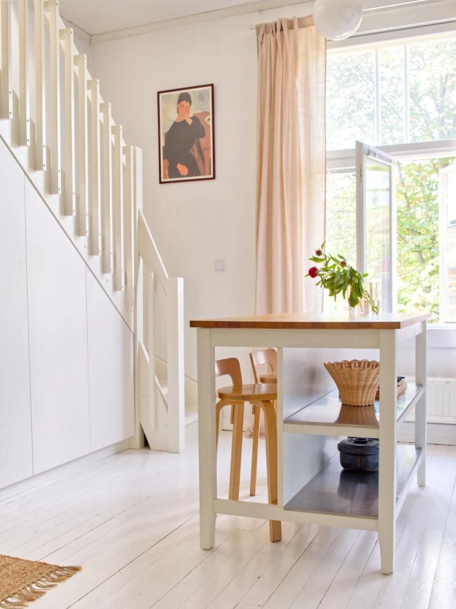 A white staircase and kitchen island