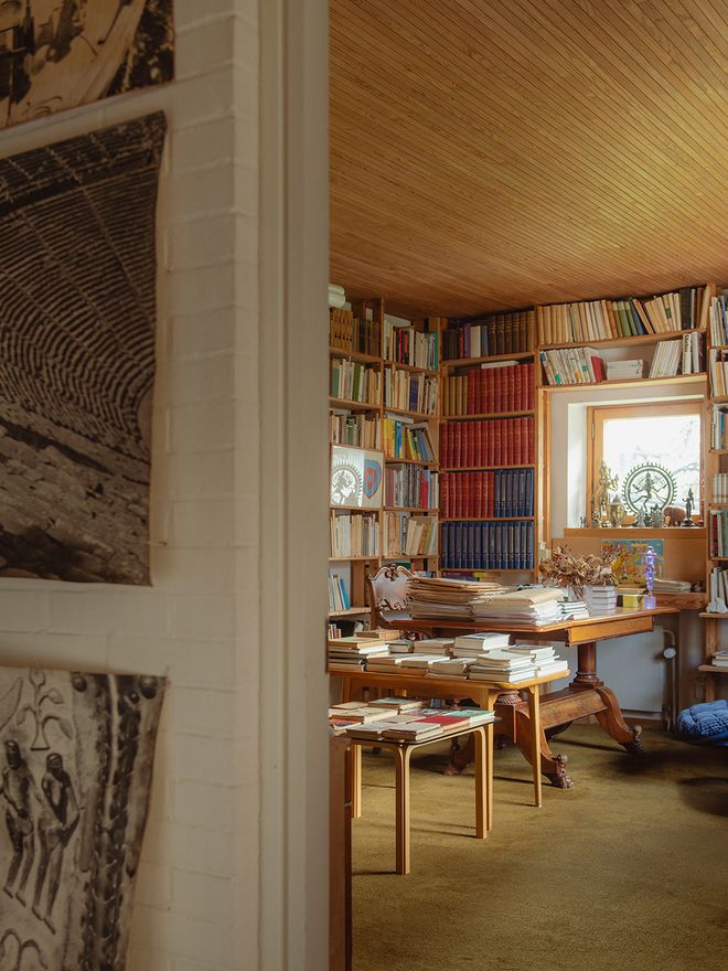 Göran Schildt's book-lined study at Villa Skeppet, with wooden shelving, a desk stacked with papers, and a window overlooking the garden