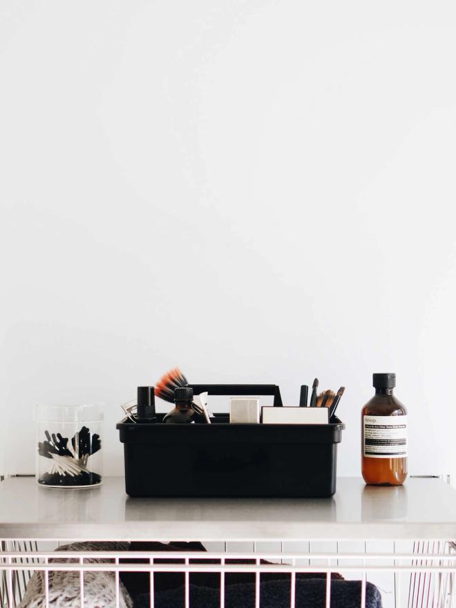 A black storage caddy filled with pens and small tools sits on a shelf