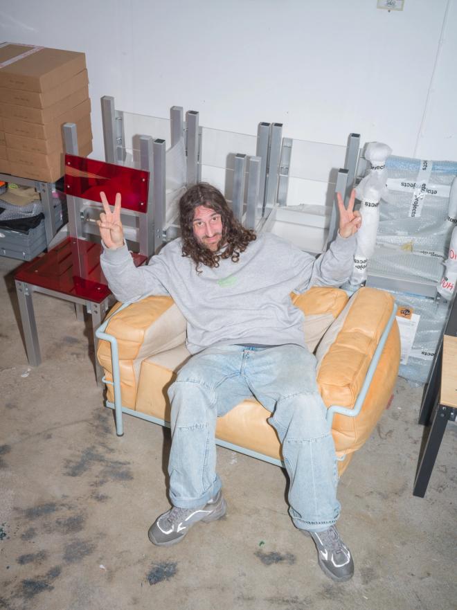 Fredrik Paulsen sits in a beige armchair, flashing peace signs with both hands.