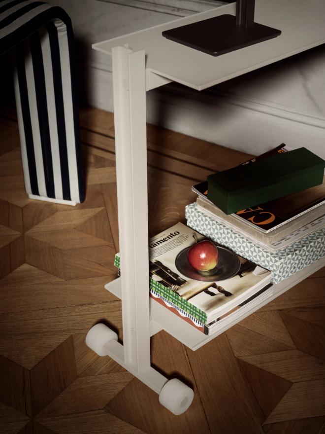 Close-up of the trolley's lower shelf holding a stack of books topped with a red apple.