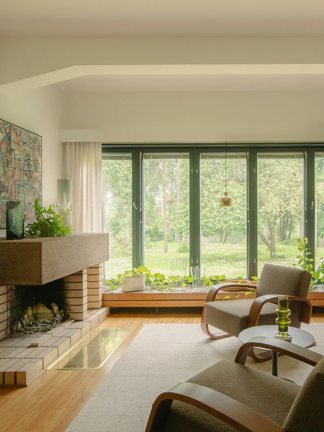 Living room with an open fireplace and large windows in a Rantala row house apartment in Sunila