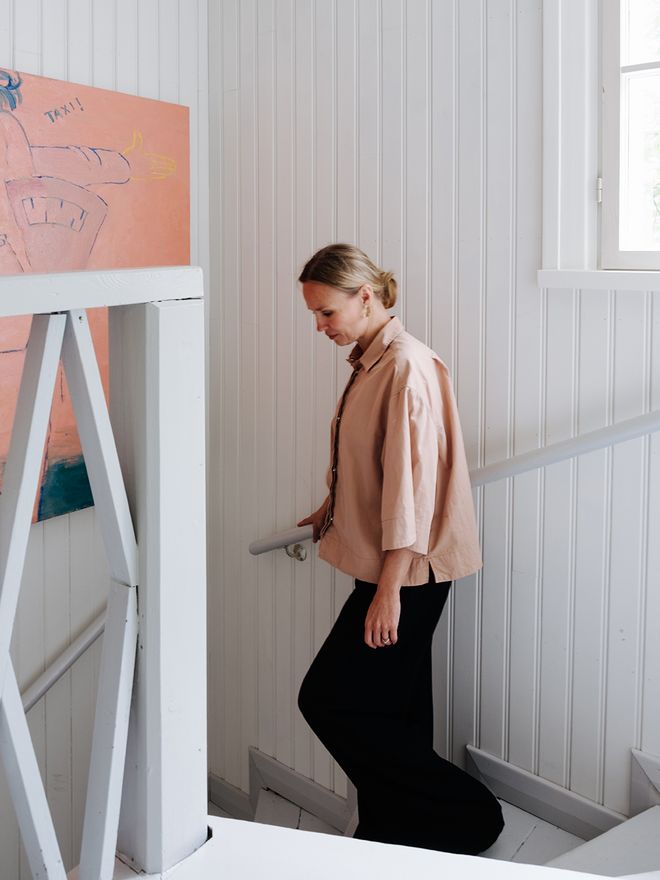 Laura Franck walking down the stairs of her home, artwork on the wall