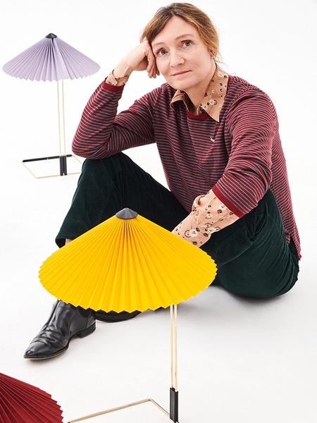 Studiokuva, jossa Inga Sempé istuu värikkäiden, vekitettyjen HAY Matin -pöytävalaisimien kanssa
