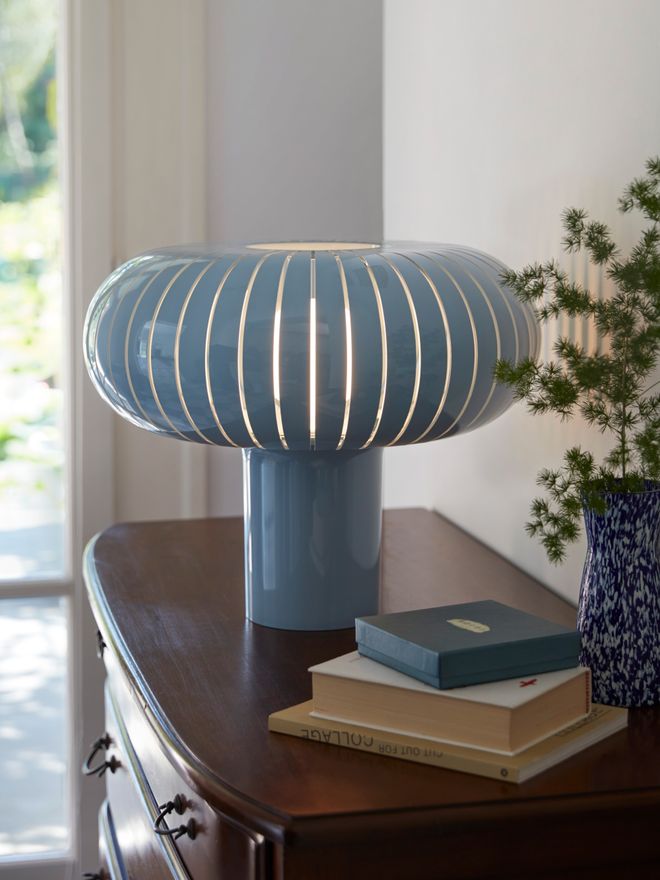 Kartell’s blue Teresa table lamp on top of a brown dresser