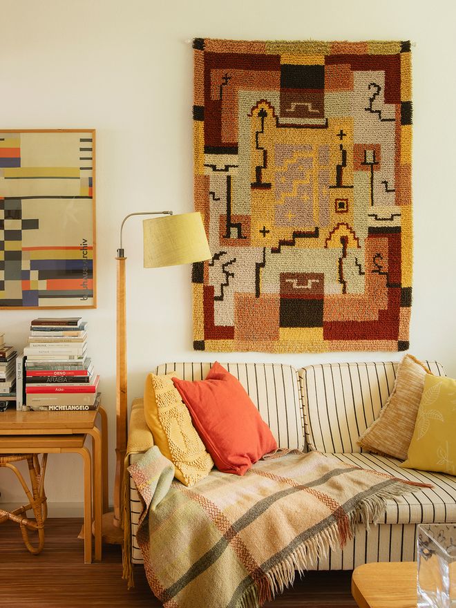 Living room with an Artek sofa and a rya rug on the wall behind it