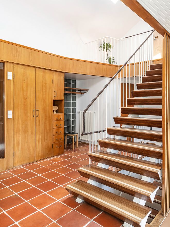 An image featuring Villa Ervi designed by architect Aarne Ervi. The photo shows the interior of the downstairs lobby with a staircase leading upwards.