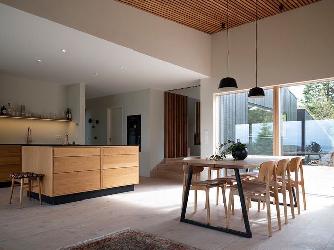 An image of the Holiday home by Þingvallavatn by KRADS architects: a leisure home located in Iceland in the middle of a picturesque scenery. This image features the buildings interior: the dining area decor and the kitchen.