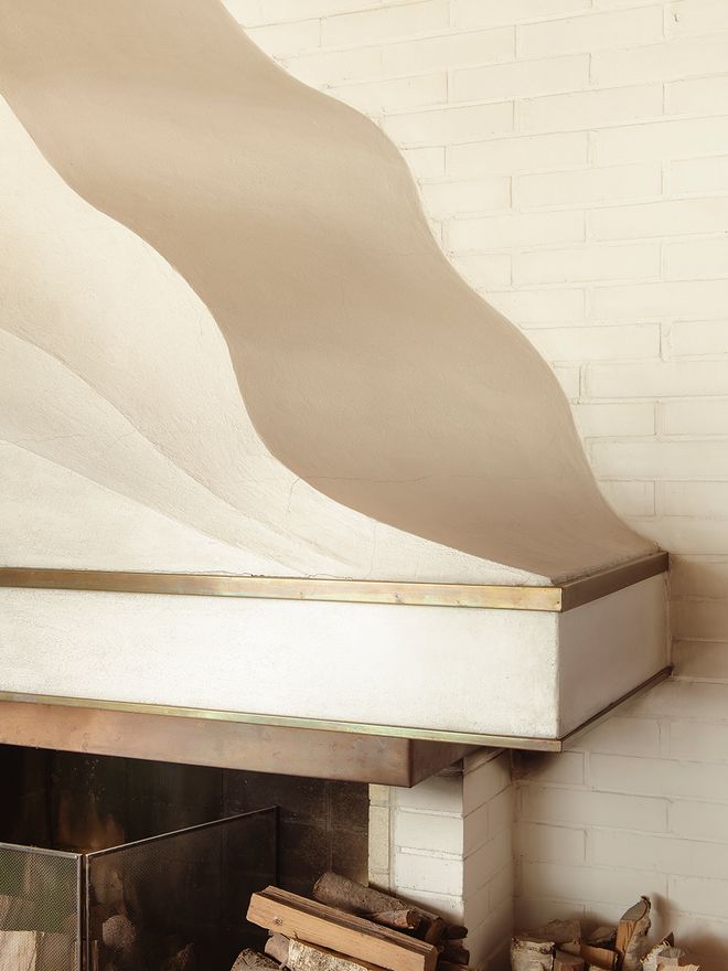 The sculptural wave-form fireplace in Villa Skeppet's living room, hand-finished by Alvar Aalto himself, with undulating white plaster curves and a brass-trimmed surround