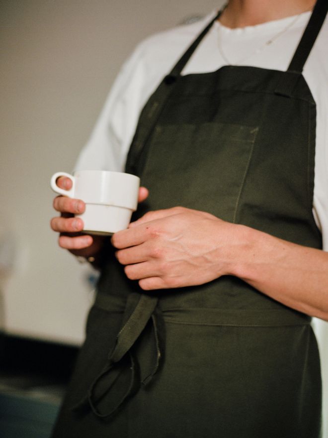 Close-up of a hand holding a porcelain Cafeteria mug from Service Projects