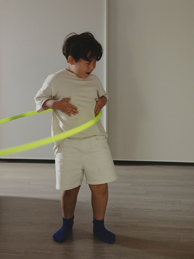 A child playing with a neon yellow hula hoop.
