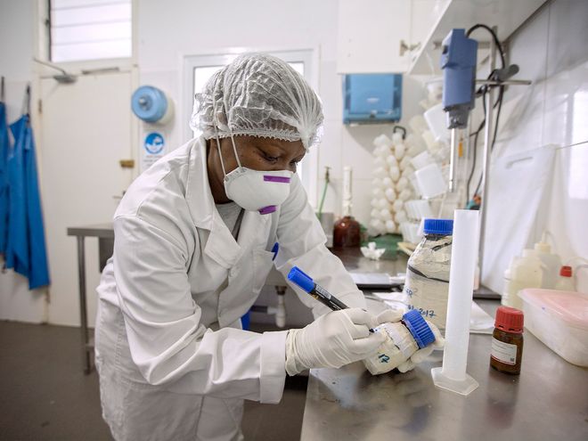 Woman working in a laboratory dressed in a white coat and protective cap.