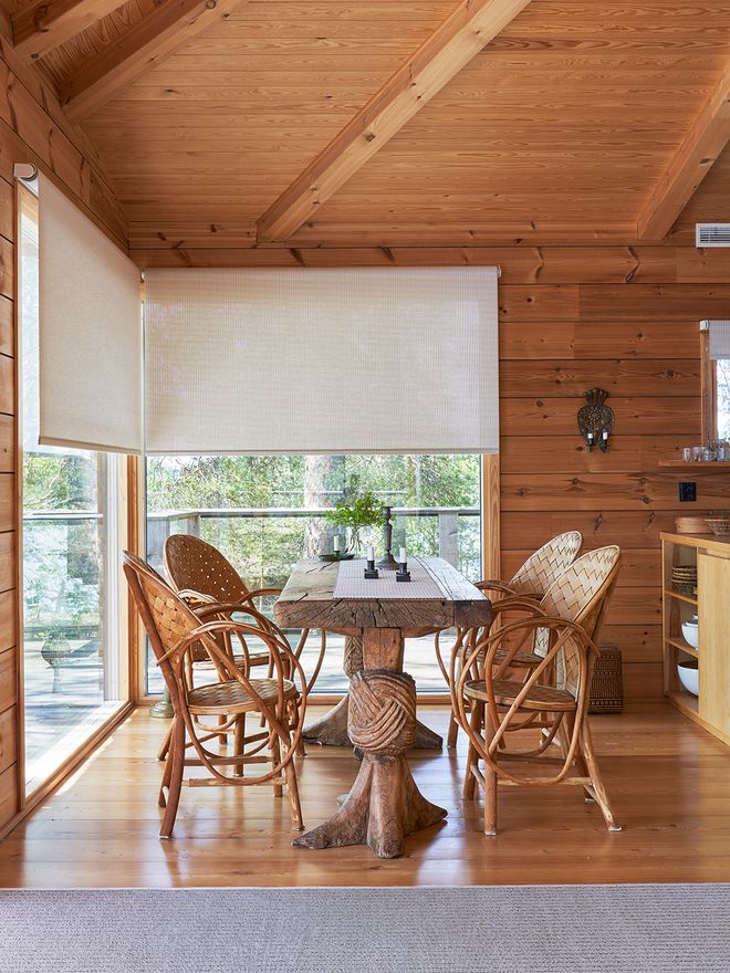 Dining area and kitchen in a lakeside cabin on Lake Saimaa. A wooden table and classic slatted chairs, a Woodnotes paper yarn rug on the floor, and roller blinds on the windows.