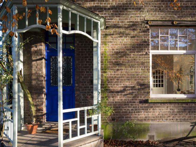 The façade of an old brick house with a blue door