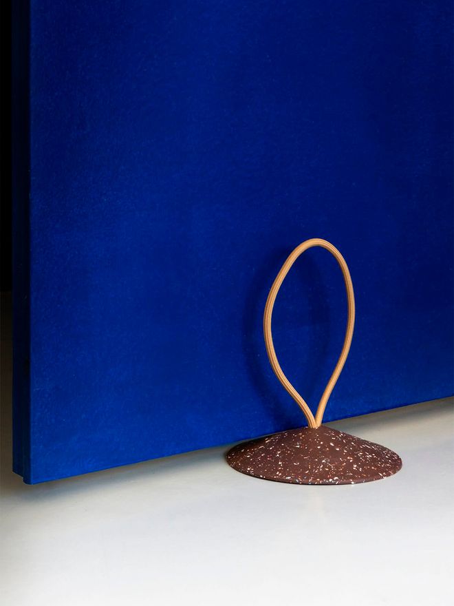 An image of a Stop doorstop holding a bright blue door open.