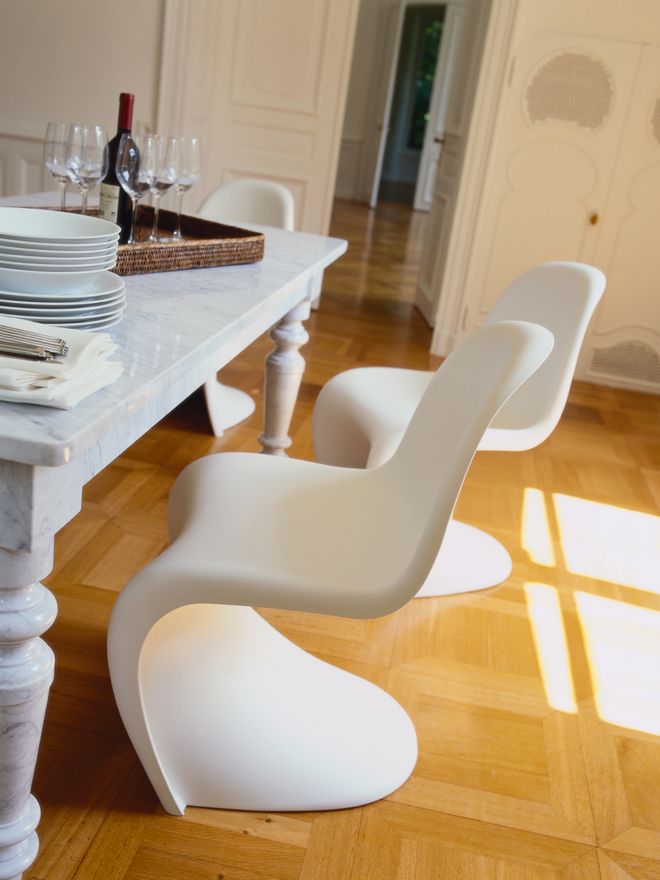 White Panton chairs by Verner Panton arranged around a dining table in a bright, sunlit room