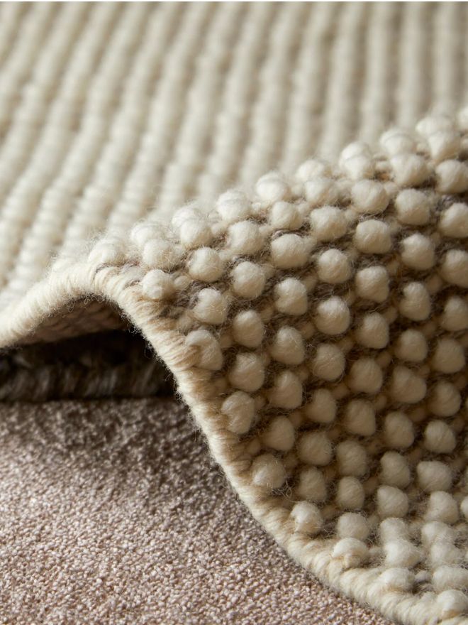 Close-up of the bead-like embossed surface at the folded edge of Woud’s Tact wool rug