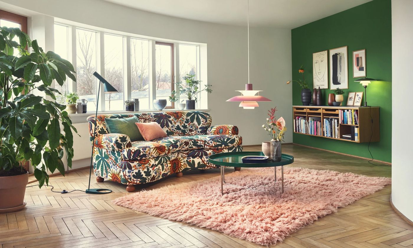Bright living room with a floral sofa, a pink shag rug and a rose pink PH 5 pendant light. A black AJ floor lamp stands next to the sofa.