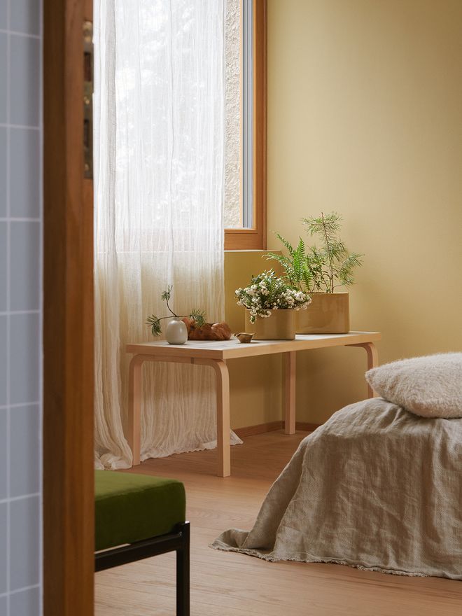 An image featuring Artek's Aalto table and Riihitie pots as part of the bedroom interior.