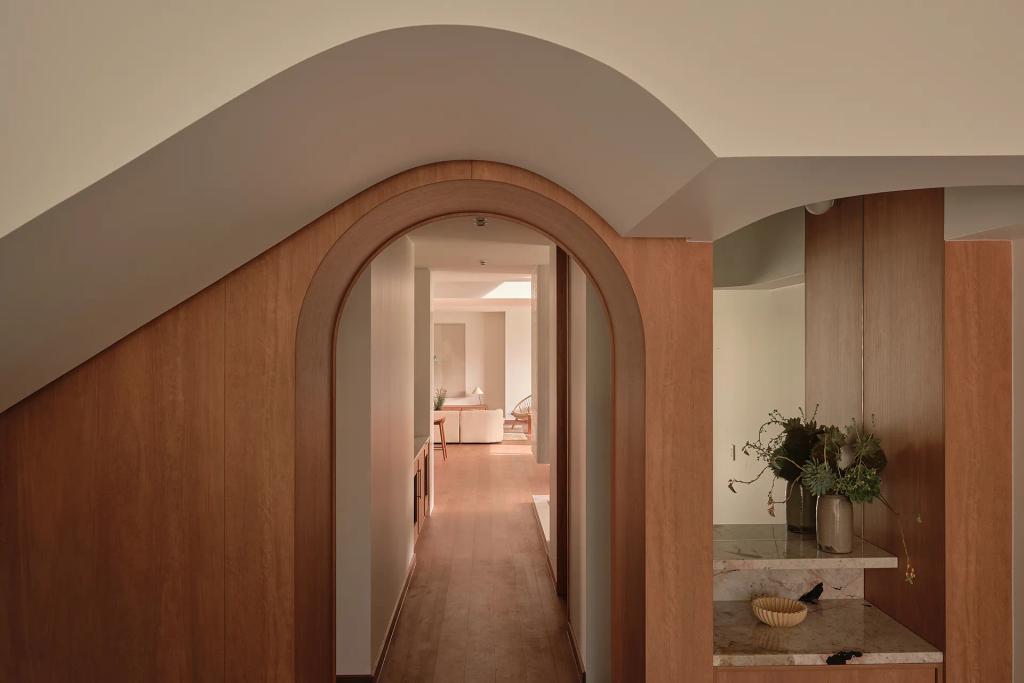Project Riverton (Wood-paneled hallway with an arched doorway leading to a bright, modern living space.)