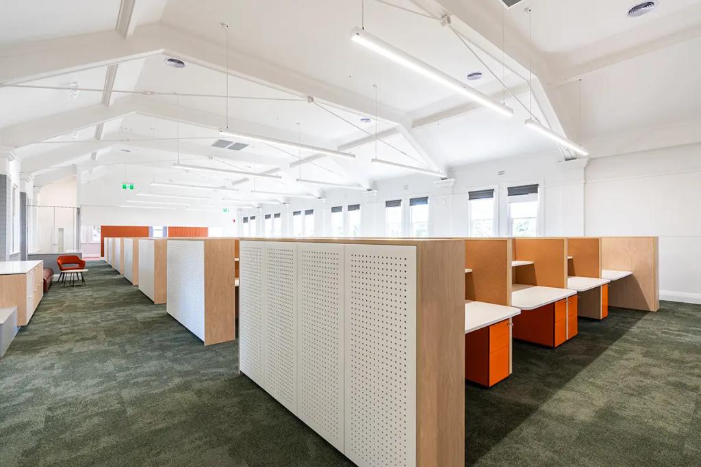 Downlands College Toowoomba Refurbishment (Spacious office with rows of wood-accented cubicles, orange drawer units, green carpet, and high white ceilings.)