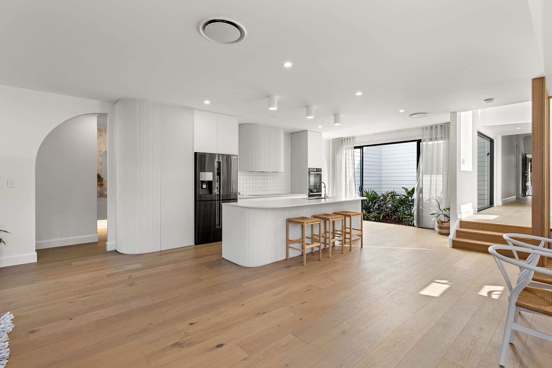Project Curve (White fluted island with curved end, matching rangehood and arched doorway)