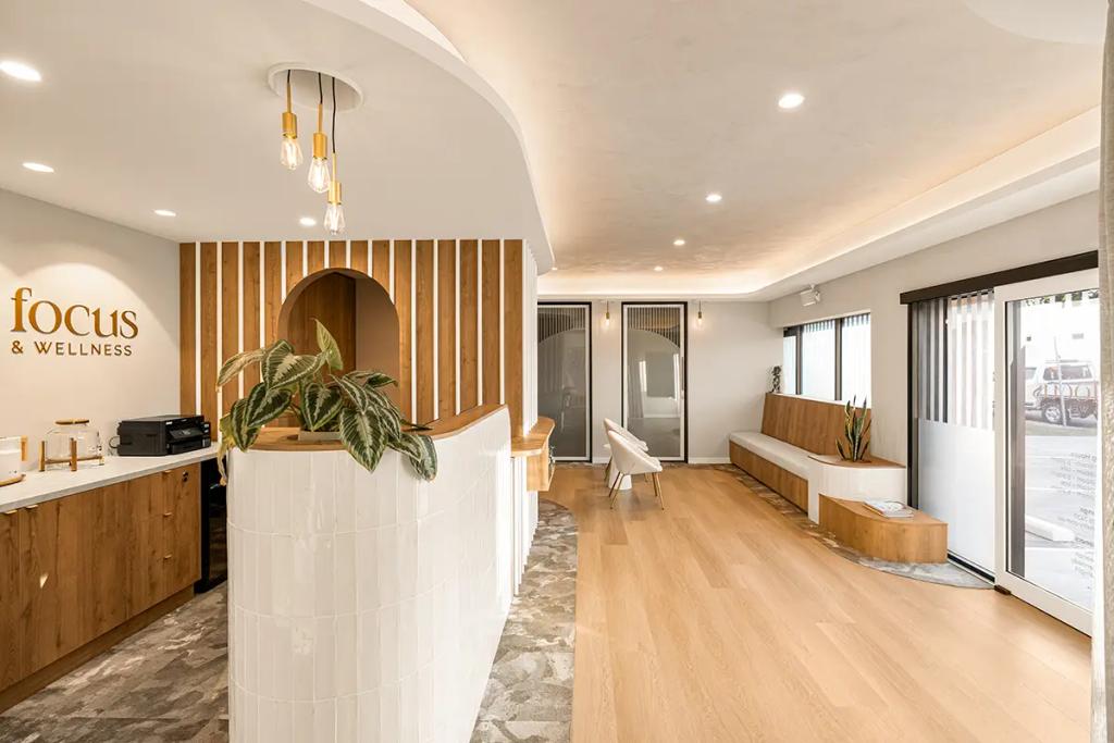 Lavish Constructions - Sole Podiatry (Clinic lobby with curved desk, wood bench, and plant.)