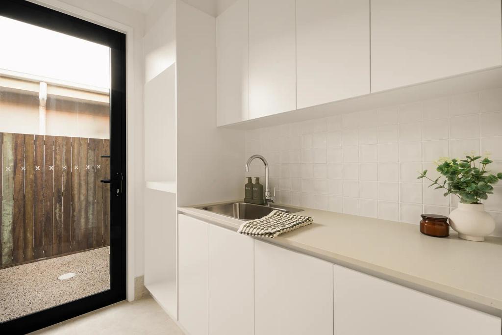 Project Ward (Modern laundry room with a stainless steel sink, white cabinets, countertop decor, and a glass door)
