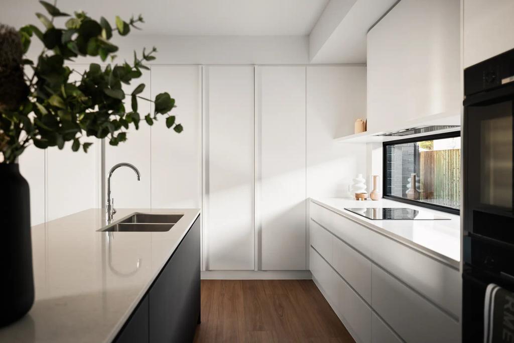 Project Ward (Modern kitchen with white cabinets, a sleek island with sink, and a window above the counter)