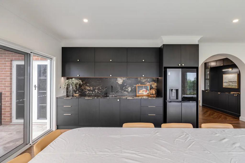 Hodgsonvale House Renovation (A sophisticated black kitchen and bar area with a granite backsplash and modern fridge.)