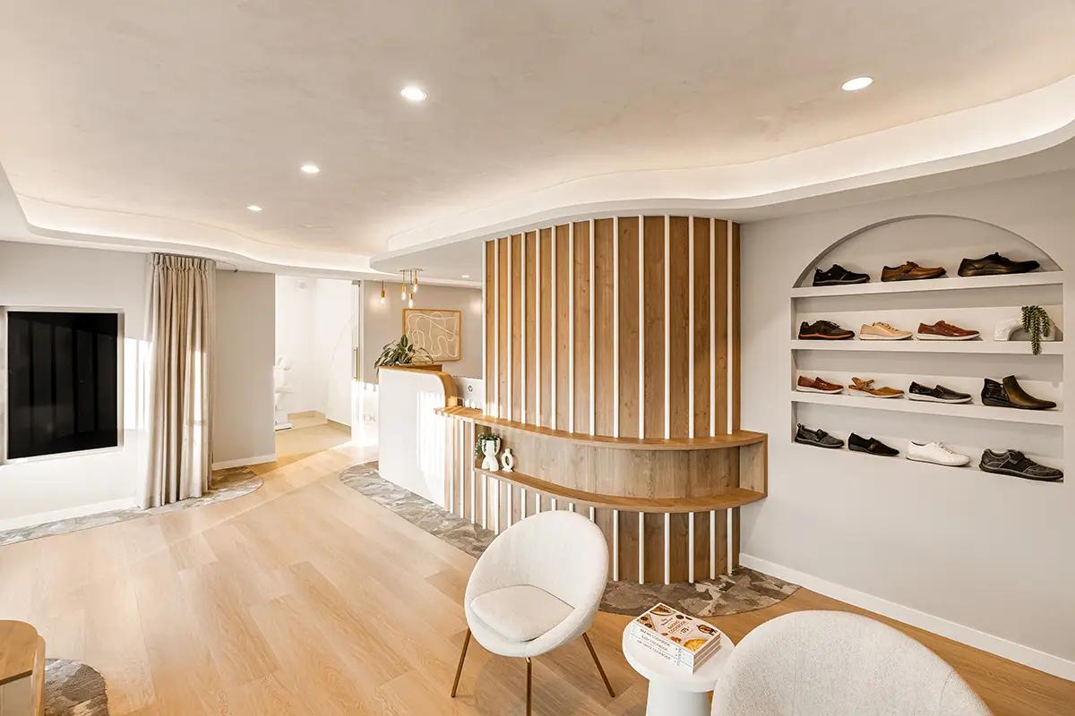 Lavish Constructions - Sole Podiatry (Clinic reception with timber-slat feature wall, arched shoe display and white tub chairs)